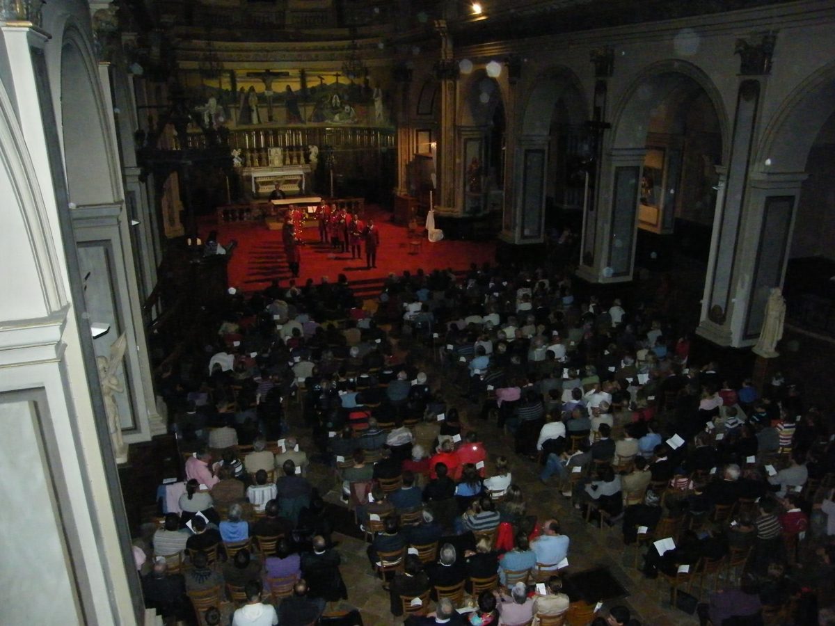 Vue depuis la tribune de l'église de la Madeleine : la nef comble, les sonneurs en habit rouge dans le chœur