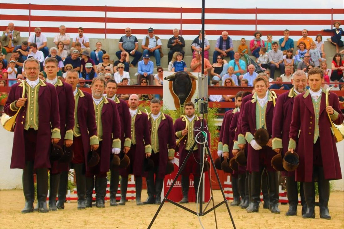 Les Trompes de Bonne en tenue bordeaux et verte, alignés dans les arènes de Maurrin devant les gradins