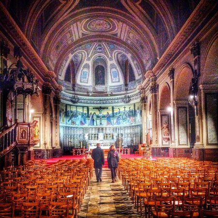 L'intérieur de l'église, la nef bordée de chaises et le chœur peint sous la coupole